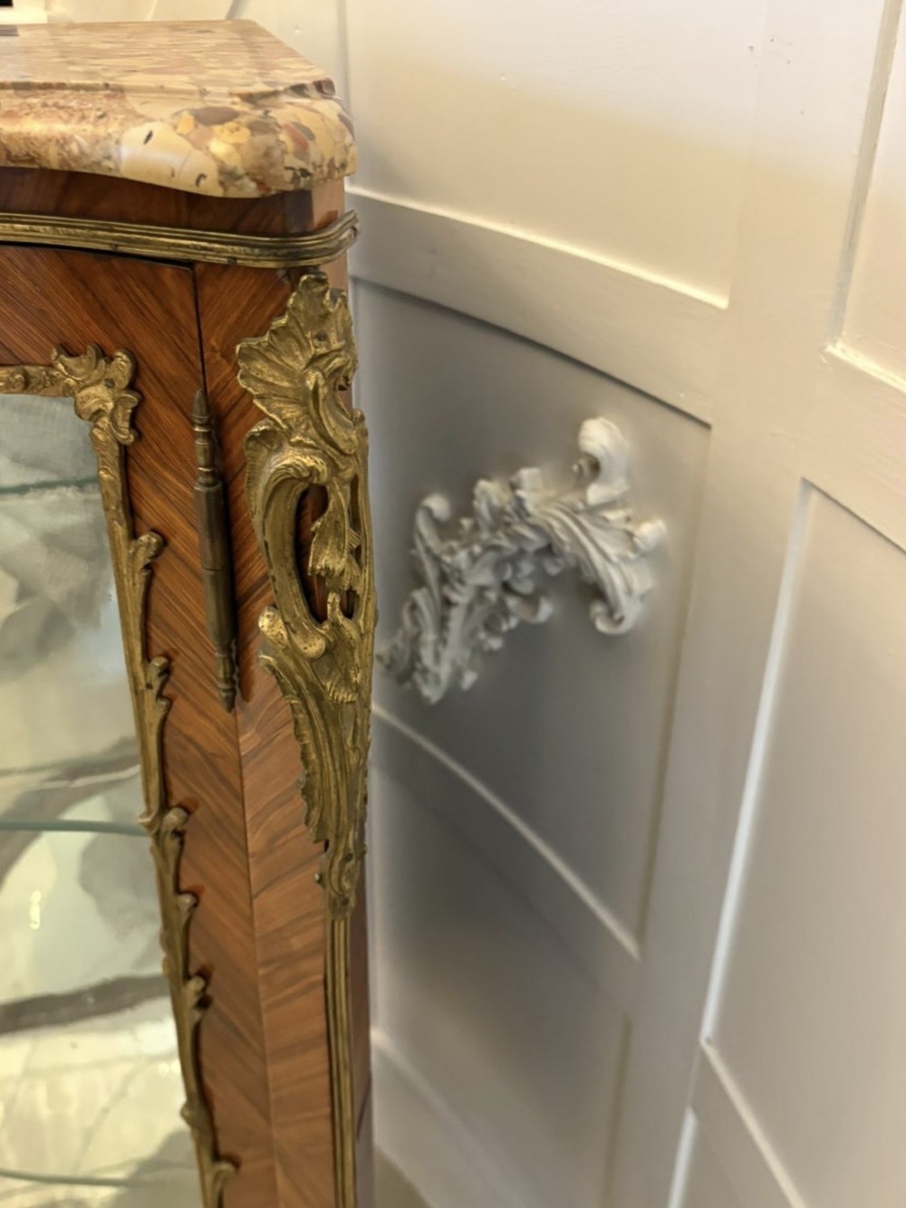 An antique French serpentine corner display cabinet crafted from kingwood with a marble top, curved glass door, internal glass shelves, and gilded ormolu mounts. View IX
