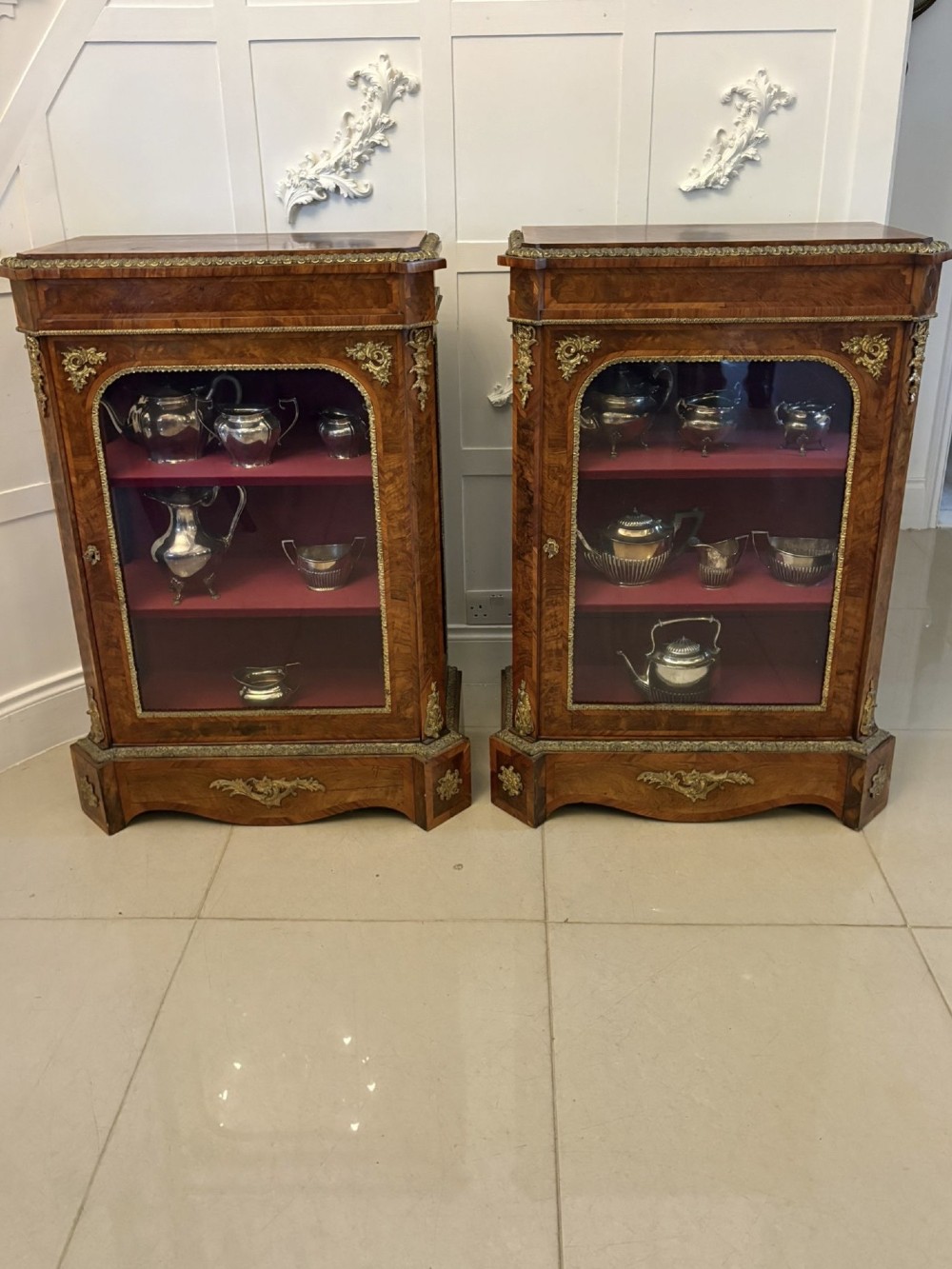 A pair of Victorian burr walnut pier cabinets featuring glazed front doors, velvet-lined interior shelves, and ornate gilt metal mounts. View II