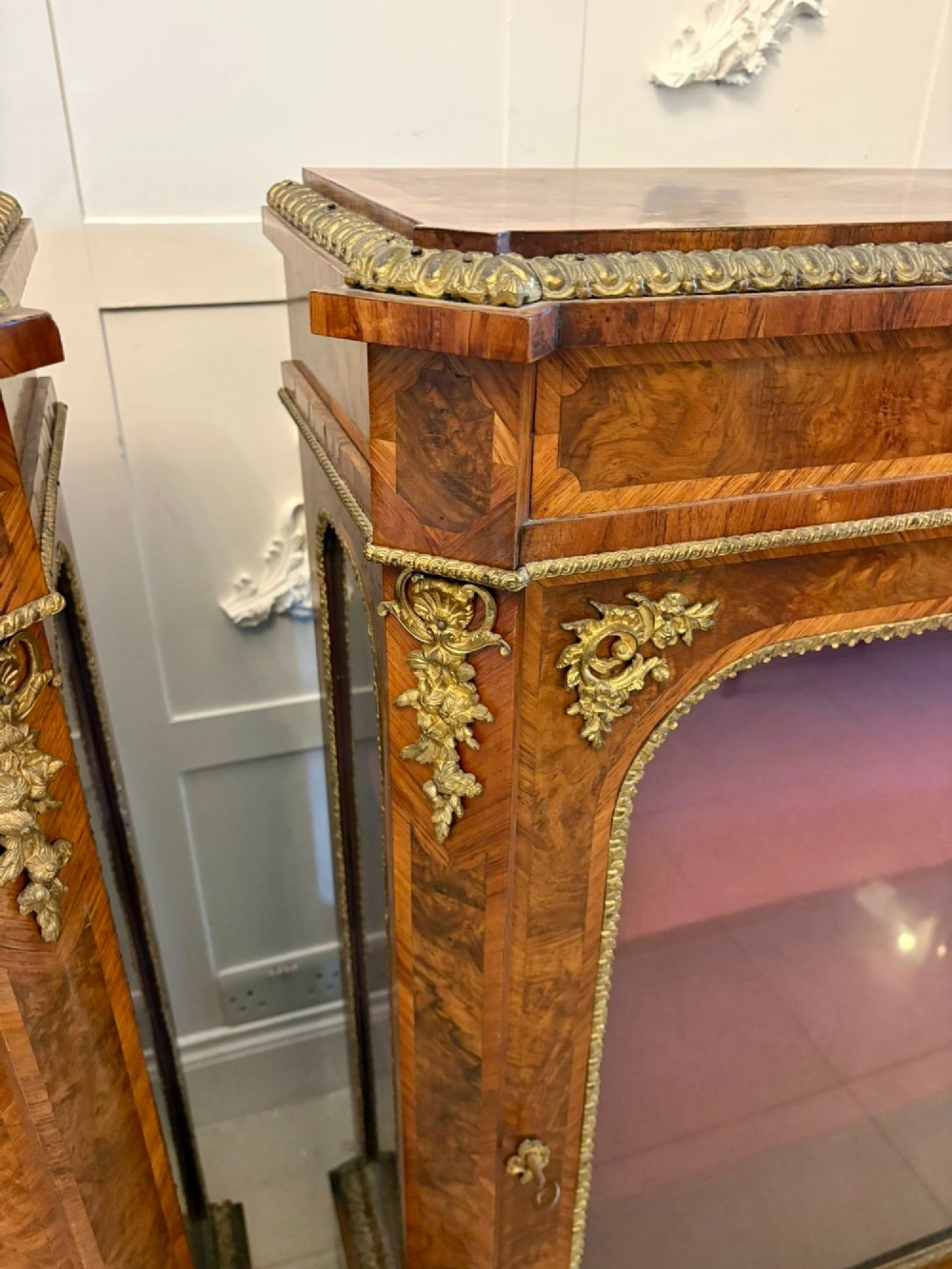 A pair of Victorian burr walnut pier cabinets featuring glazed front doors, velvet-lined interior shelves, and ornate gilt metal mounts. View IV