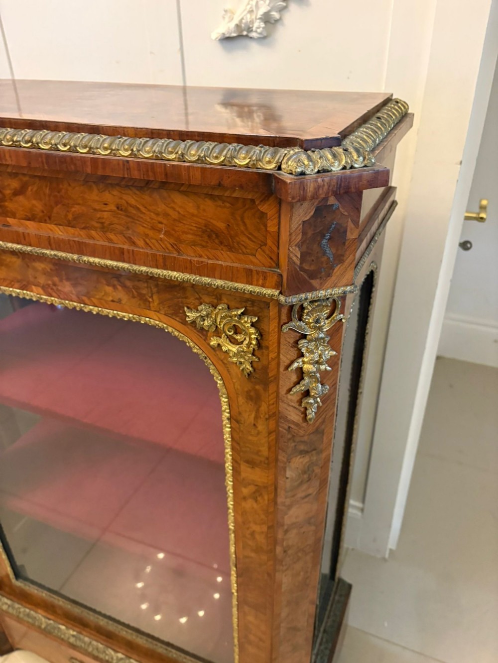 A pair of Victorian burr walnut pier cabinets featuring glazed front doors, velvet-lined interior shelves, and ornate gilt metal mounts. View VI