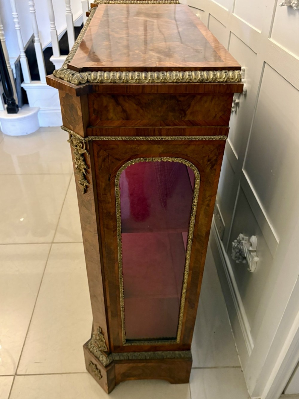 A pair of Victorian burr walnut pier cabinets featuring glazed front doors, velvet-lined interior shelves, and ornate gilt metal mounts. View VIII
