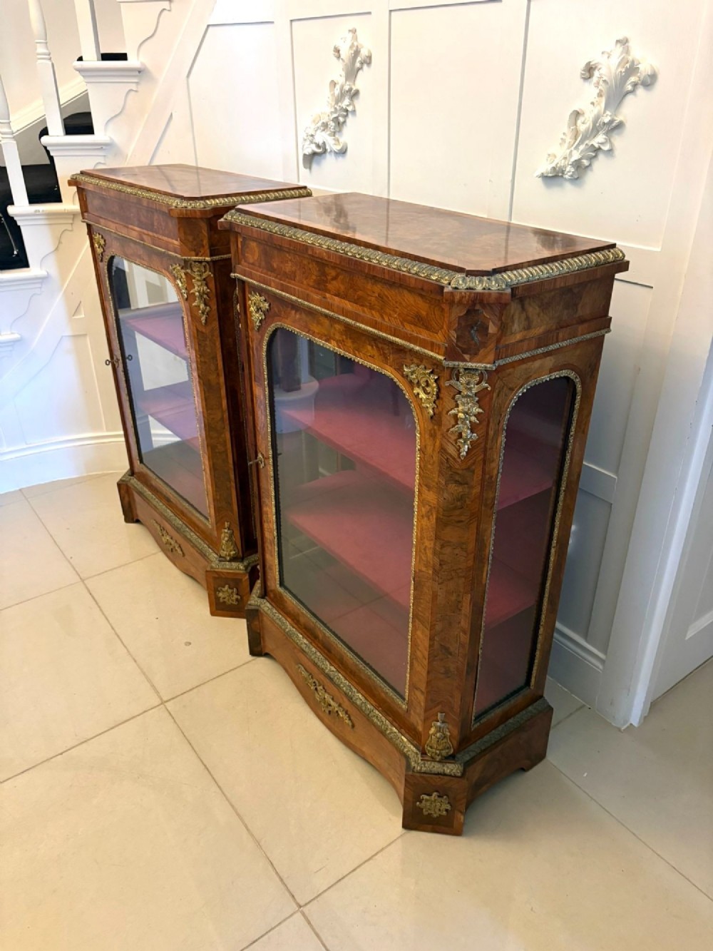 A pair of Victorian burr walnut pier cabinets featuring glazed front doors, velvet-lined interior shelves, and ornate gilt metal mounts. View XIII