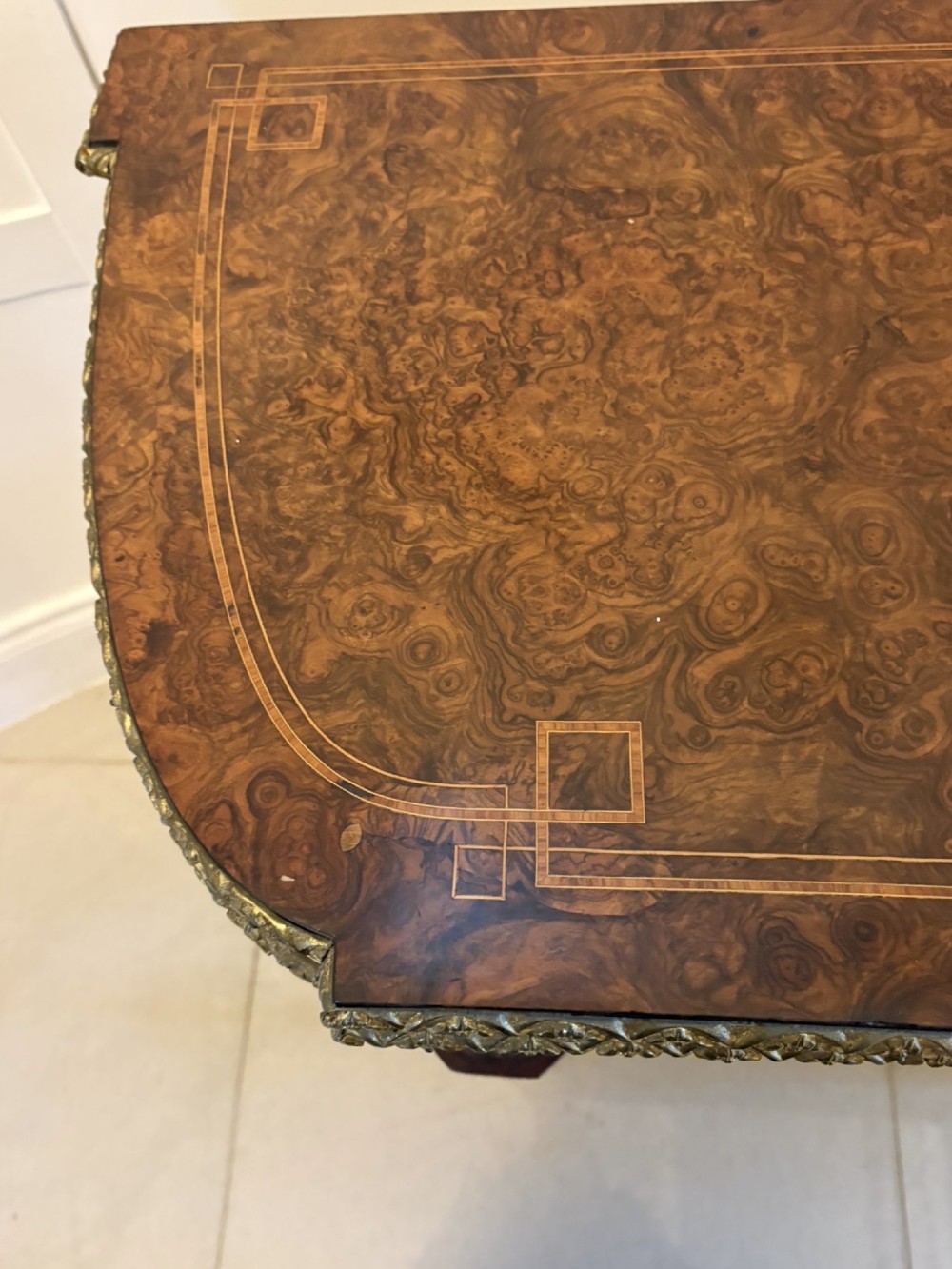 A Victorian burr walnut fold-over card table featuring geometric inlay, turned support legs on castors, and decorative brass edge moulding. View IX