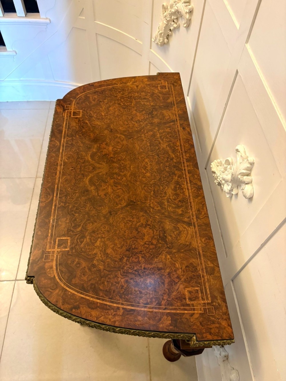 A Victorian burr walnut fold-over card table featuring geometric inlay, turned support legs on castors, and decorative brass edge moulding. View XI
