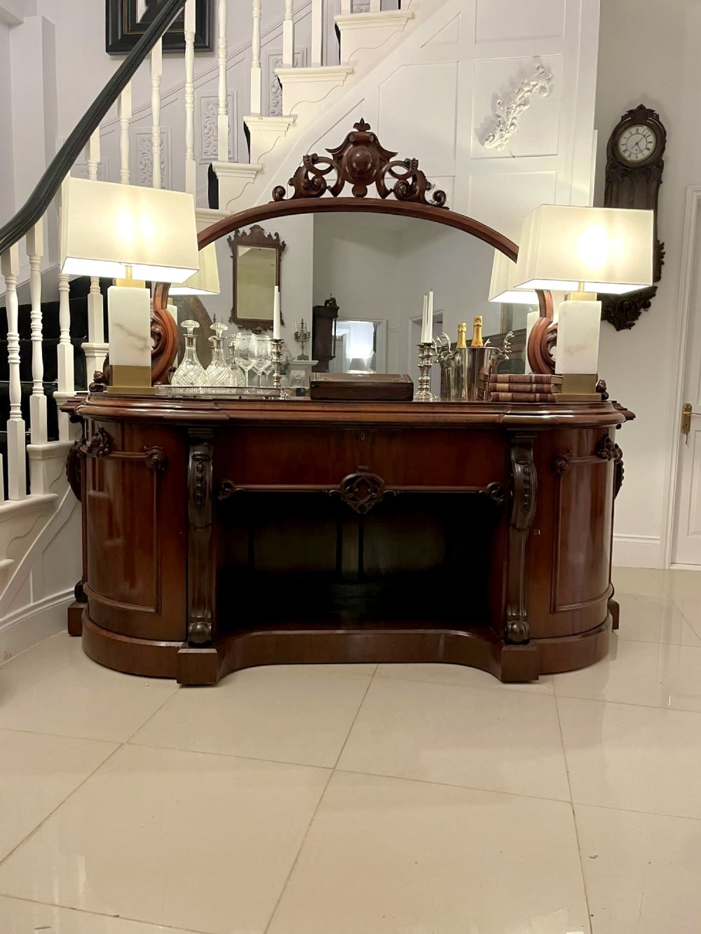 A Victorian carved mahogany sideboard featuring a curved front, open central bay, flanked cupboards, and a large arched mirror backrest adorned with scroll carving. View II