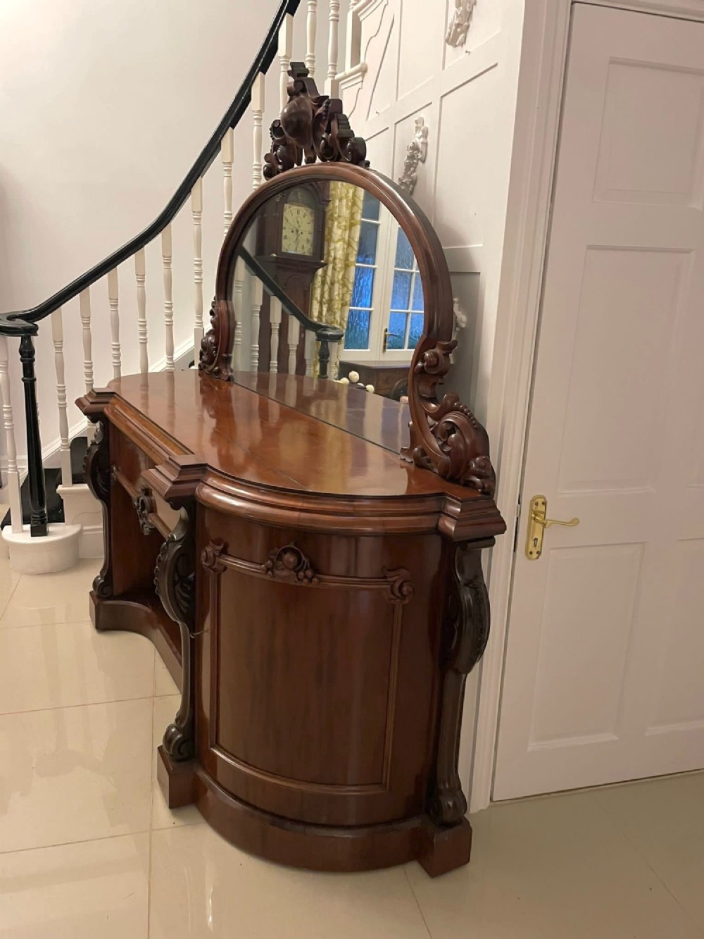 A Victorian carved mahogany sideboard featuring a curved front, open central bay, flanked cupboards, and a large arched mirror backrest adorned with scroll carving. View VIII