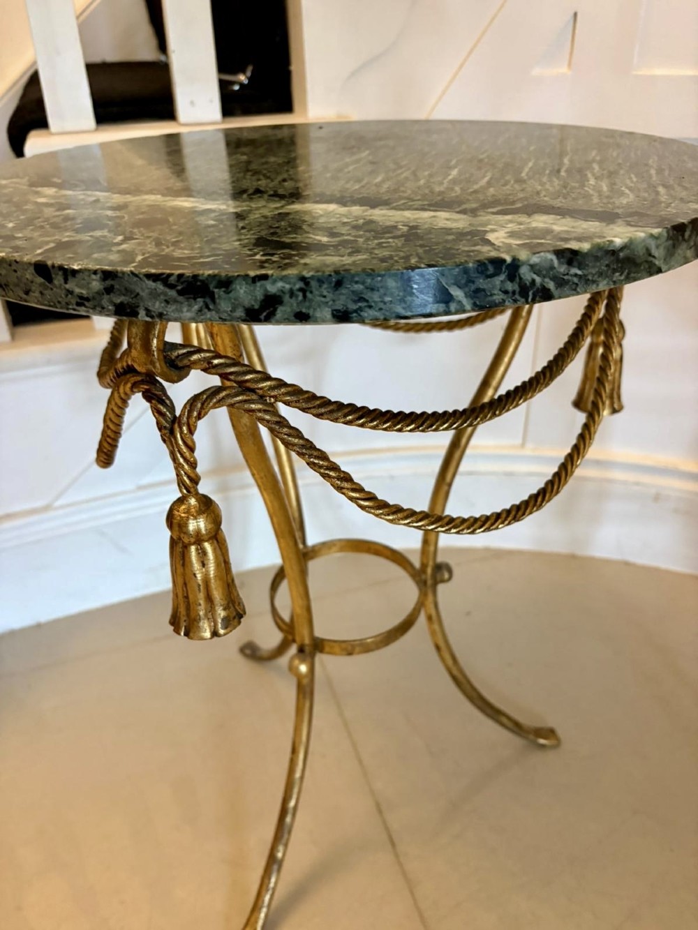 A pair of circular Italian side tables featuring dark green marble tops supported by gilt metal legs adorned with draped rope and tassel motifs. View X