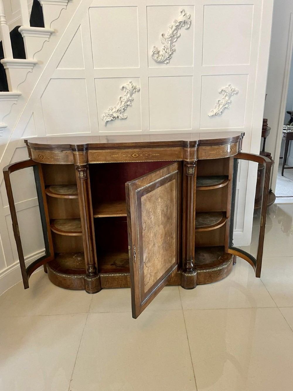 A Victorian burr walnut credenza with a central marquetry inlaid door, gilt ormolu mounts, and two curved glass side display cabinets. View IX