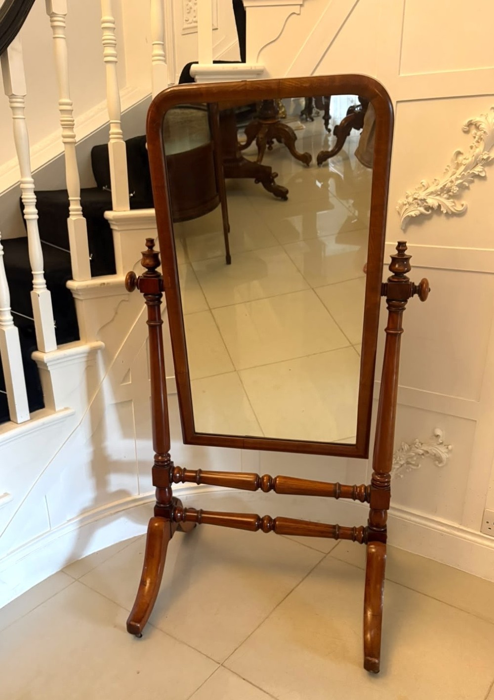 A Victorian mahogany freestanding cheval mirror featuring turned upright pillars, arched legs, and a swivelling full-length mirror frame.