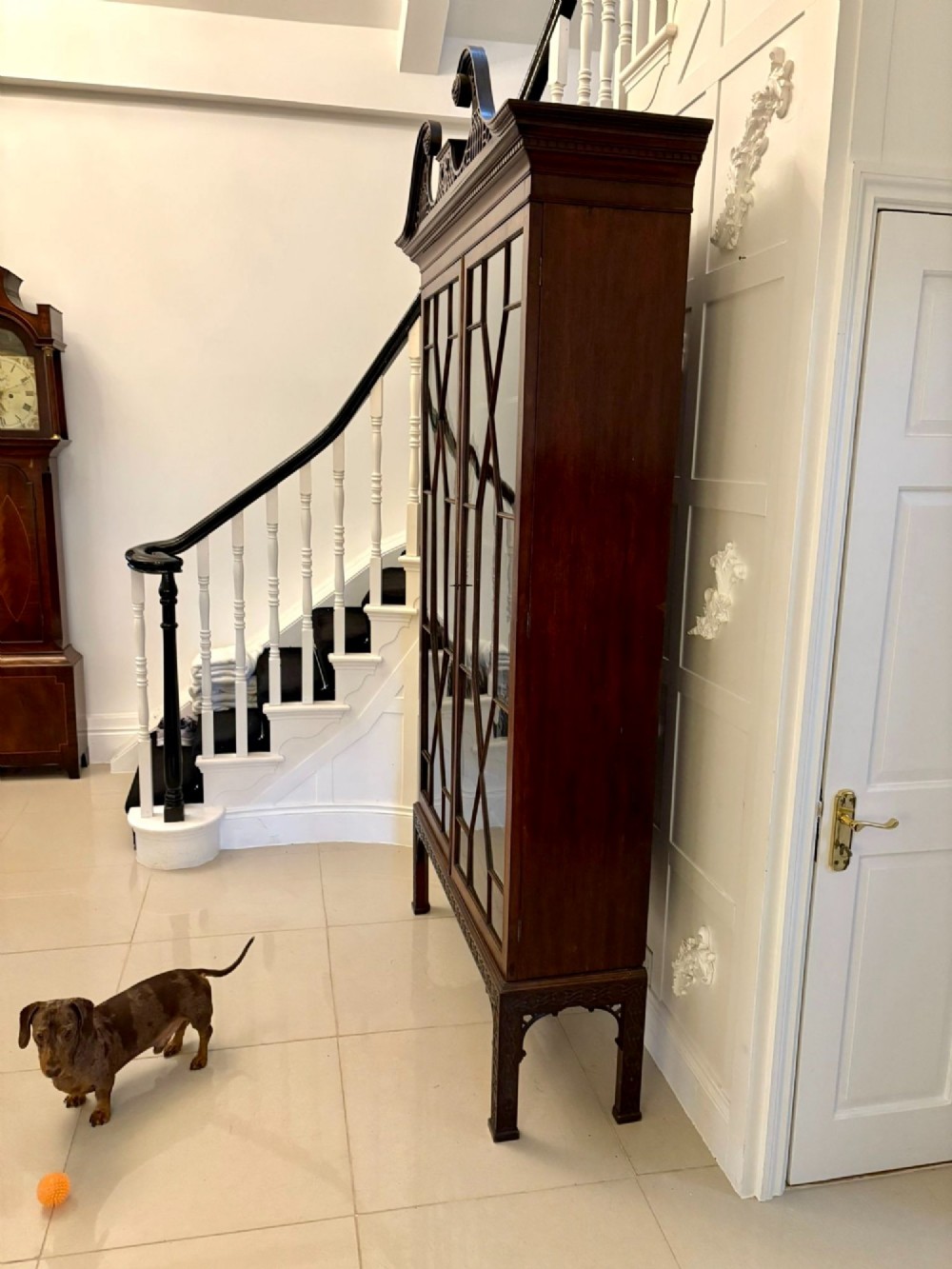 A tall antique Victorian mahogany bookcase featuring a pierced swan-neck pediment, astragal glazed double doors, and carved legs. View III