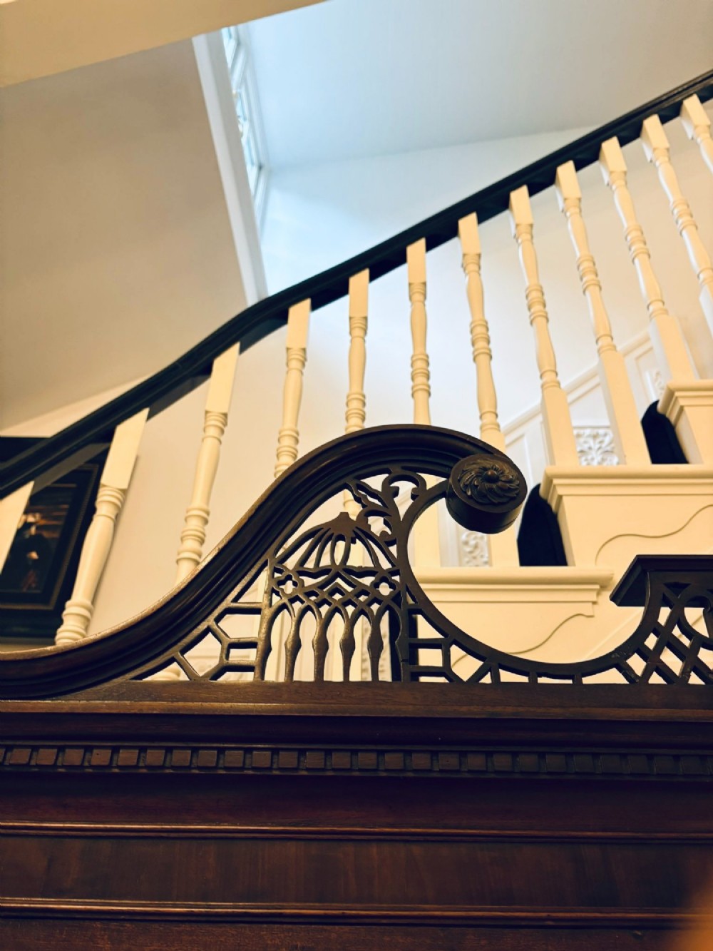 A tall antique Victorian mahogany bookcase featuring a pierced swan-neck pediment, astragal glazed double doors, and carved legs. View IV