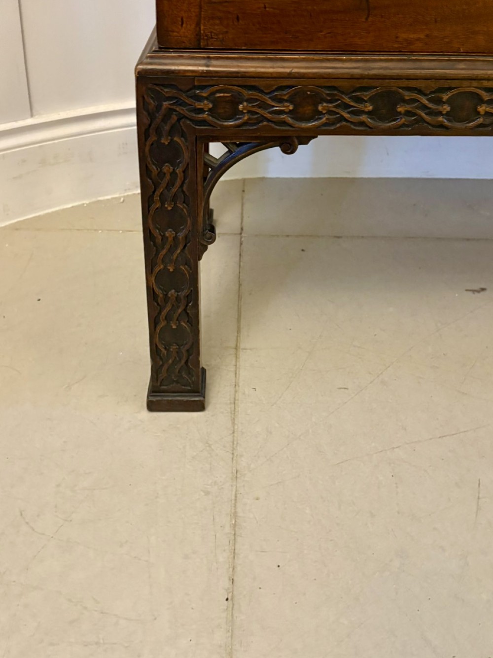 A tall antique Victorian mahogany bookcase featuring a pierced swan-neck pediment, astragal glazed double doors, and carved legs. View V