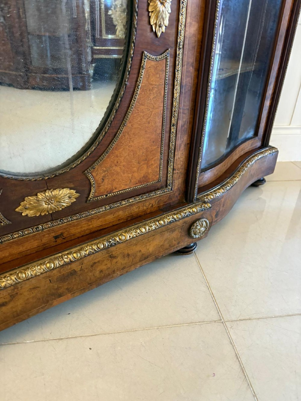 A Victorian burr walnut credenza featuring a central oval mirrored door flanked by curved bow-front glass doors and gilt ormolu mounts. View V