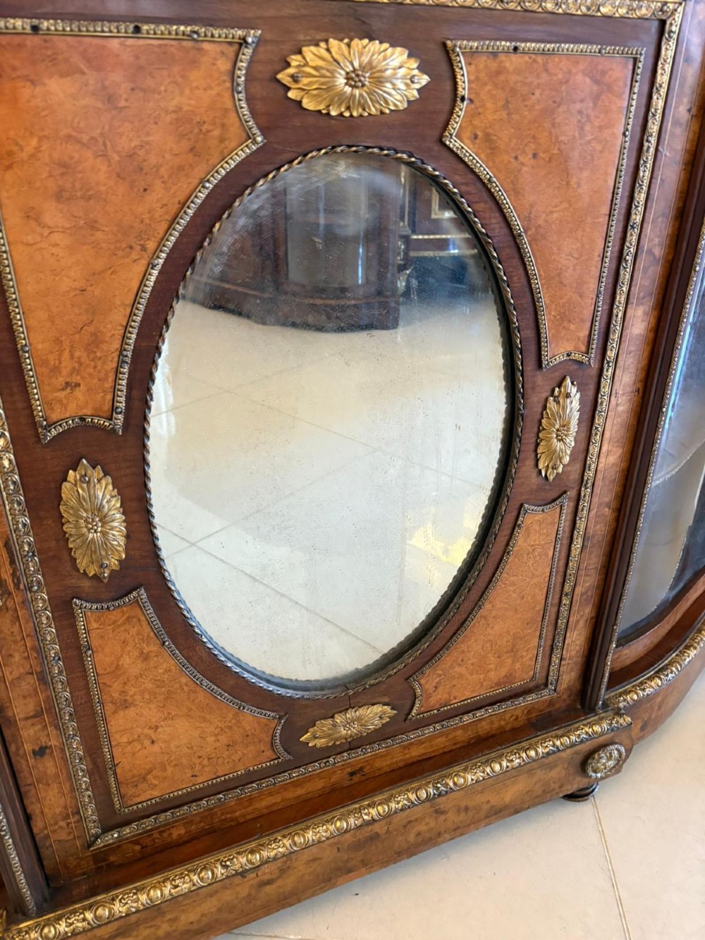 A Victorian burr walnut credenza featuring a central oval mirrored door flanked by curved bow-front glass doors and gilt ormolu mounts. View IX