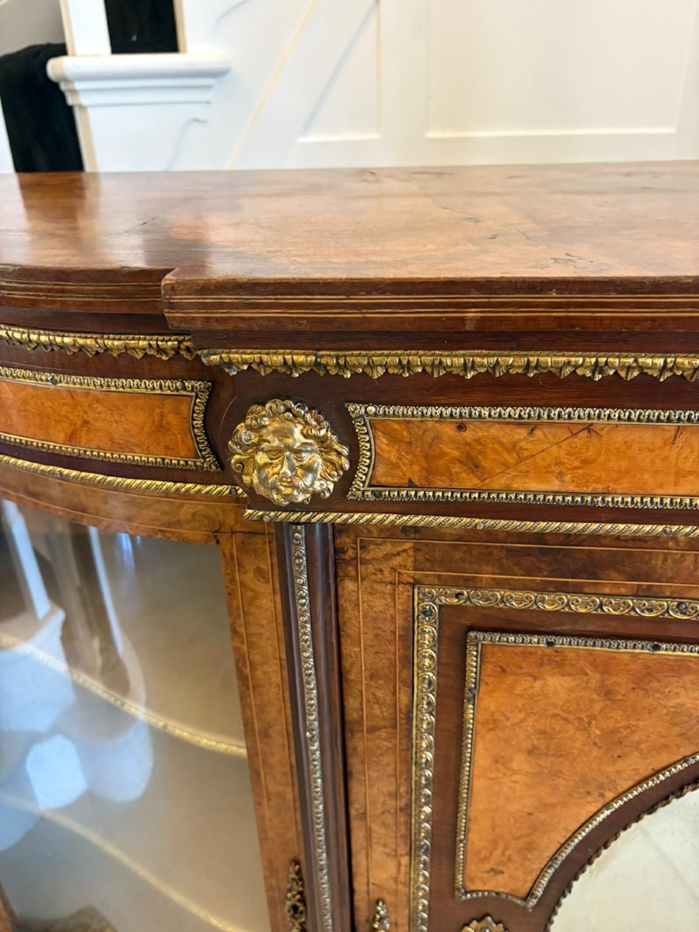 A Victorian burr walnut credenza featuring a central oval mirrored door flanked by curved bow-front glass doors and gilt ormolu mounts. View XI