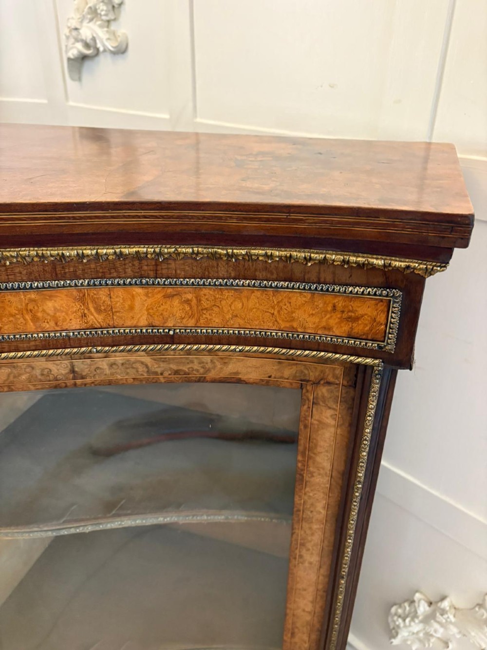 A Victorian burr walnut credenza featuring a central oval mirrored door flanked by curved bow-front glass doors and gilt ormolu mounts. View XII