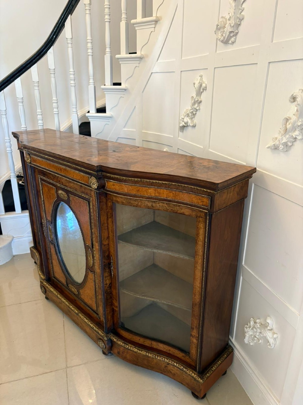 A Victorian burr walnut credenza featuring a central oval mirrored door flanked by curved bow-front glass doors and gilt ormolu mounts. View XIII