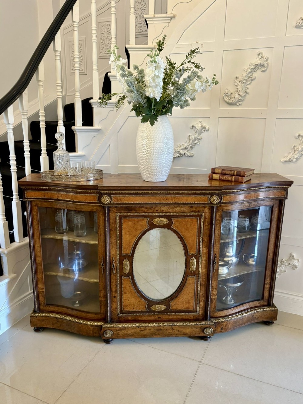 A Victorian burr walnut credenza featuring a central oval mirrored door flanked by curved bow-front glass doors and gilt ormolu mounts. View XV