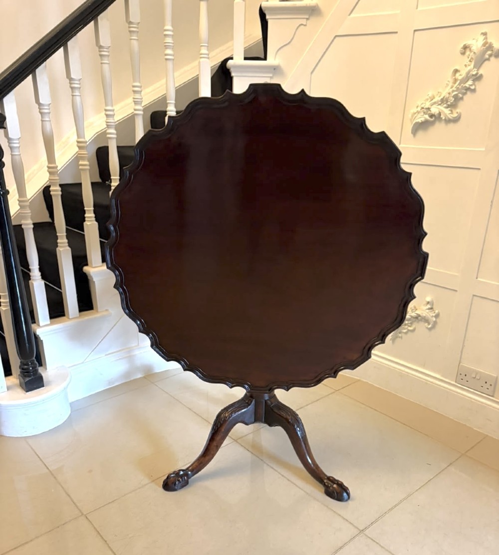 A mahogany George III style tilt-top centre table featuring a scalloped piecrust edge, central pedestal, and tripod cabriole legs with claw and ball feet.