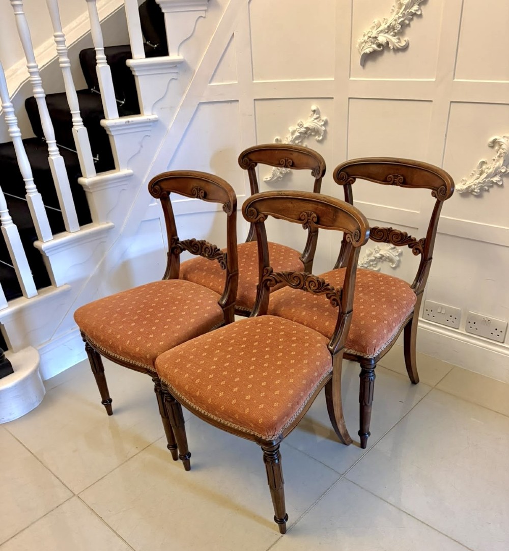 A set of four antique Regency rosewood dining chairs featuring carved scroll top rails and pattern-upholstered seats on turned front legs. View XV