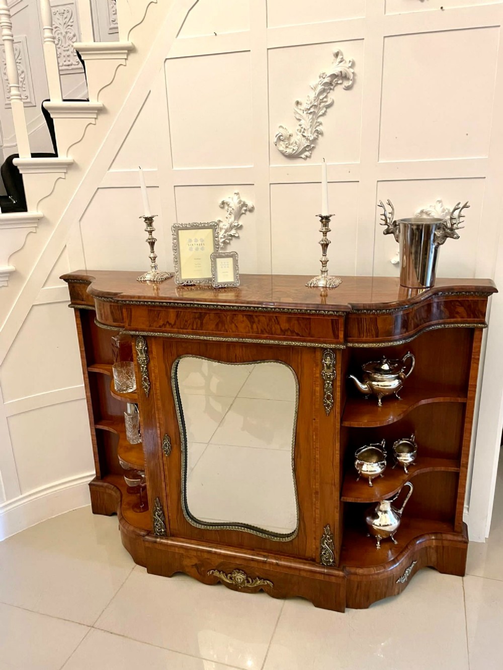 A Victorian burr walnut credenza featuring a central glass door, open serpentine display shelves, and detailed brass ormolu mounts. View V