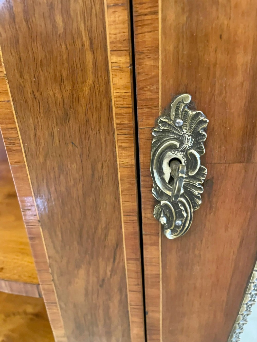A Victorian burr walnut credenza featuring a central glass door, open serpentine display shelves, and detailed brass ormolu mounts. View VIII