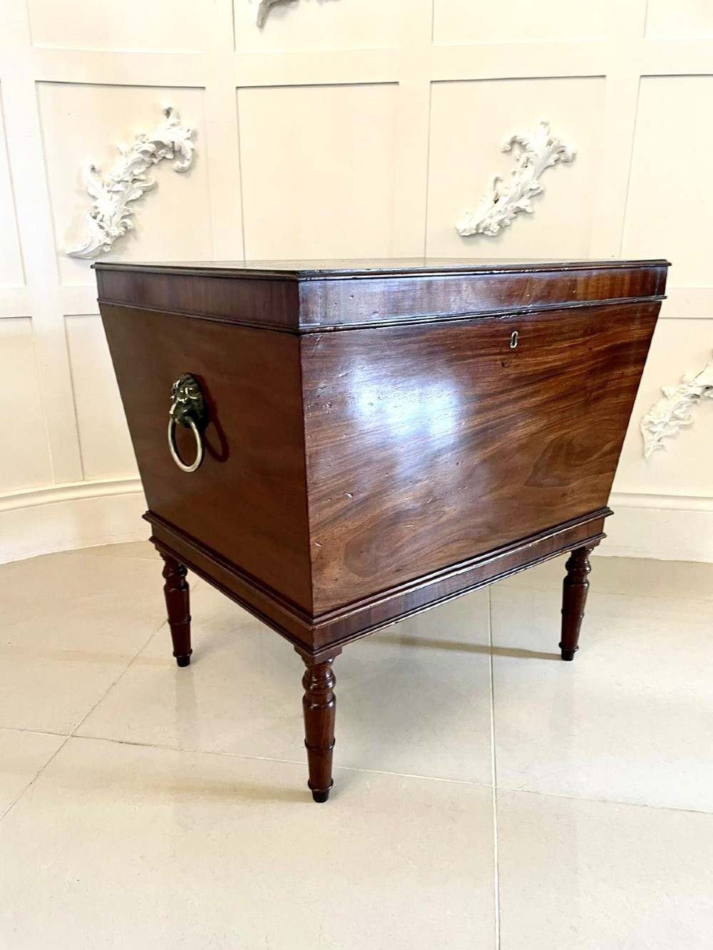 A Georgian mahogany cellarette featuring a tapered rectangular body on turned legs with brass lion-mask side handles and a keyhole lid. View XII