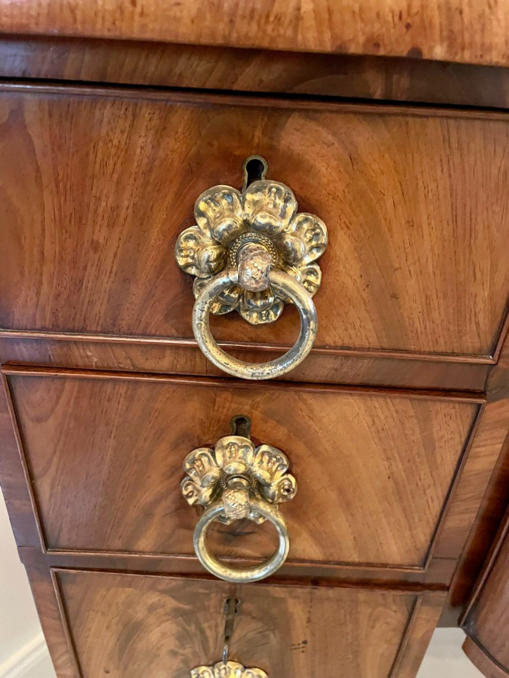 A Regency flame mahogany kneehole desk featuring twin pedestals with multiple drawers, brass ring handles, turned feet, and a shaped back gallery. View VII