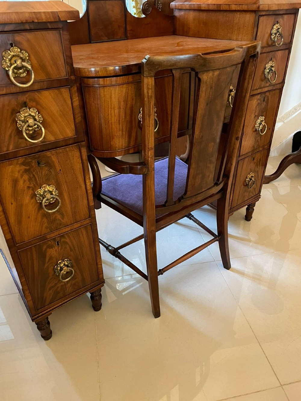A Regency flame mahogany kneehole desk featuring twin pedestals with multiple drawers, brass ring handles, turned feet, and a shaped back gallery. View VIII