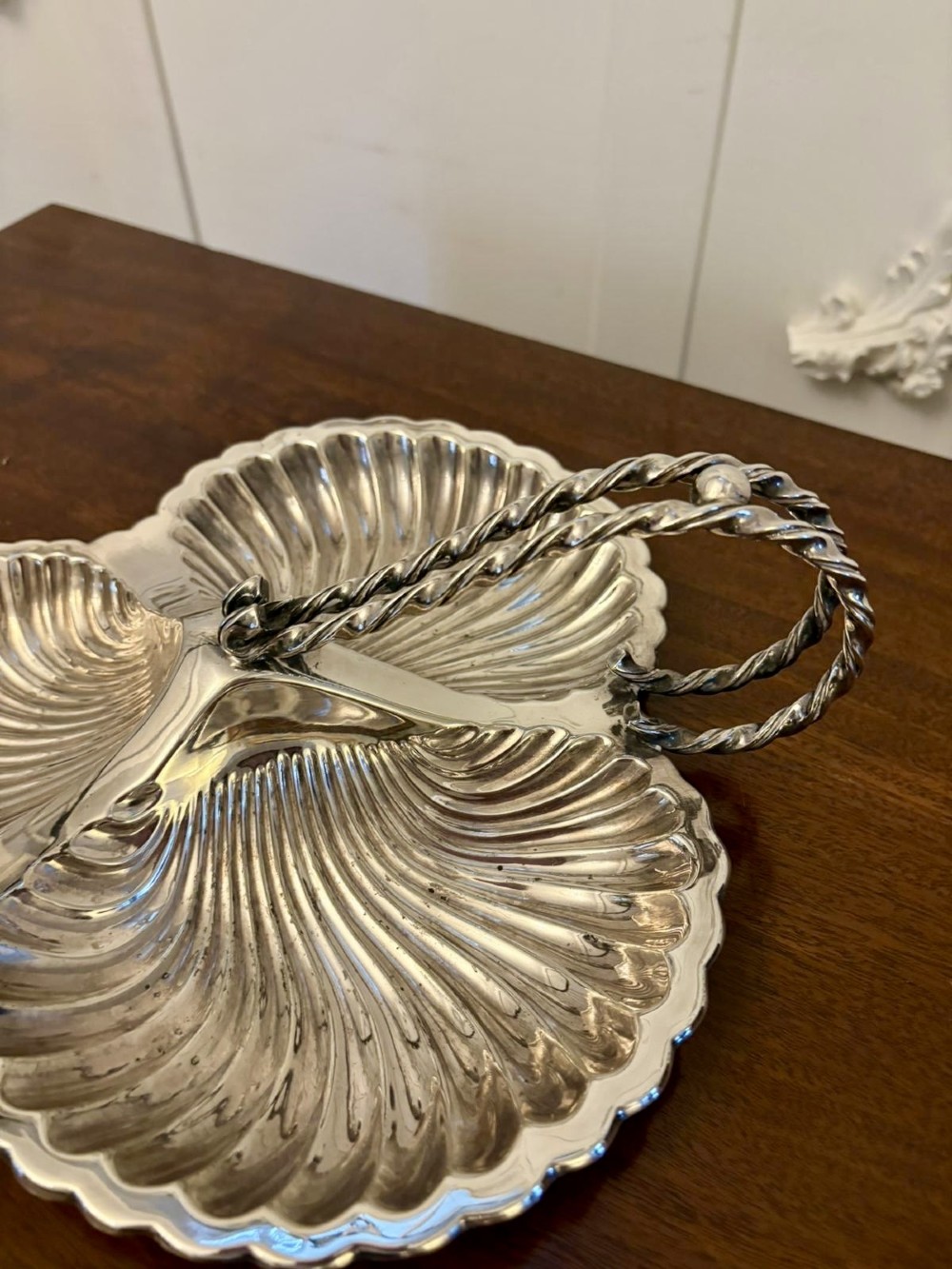 An Edwardian silver-plated tripartite serving dish featuring three fluted shell-shaped compartments joined by a central twisted handle. View IV