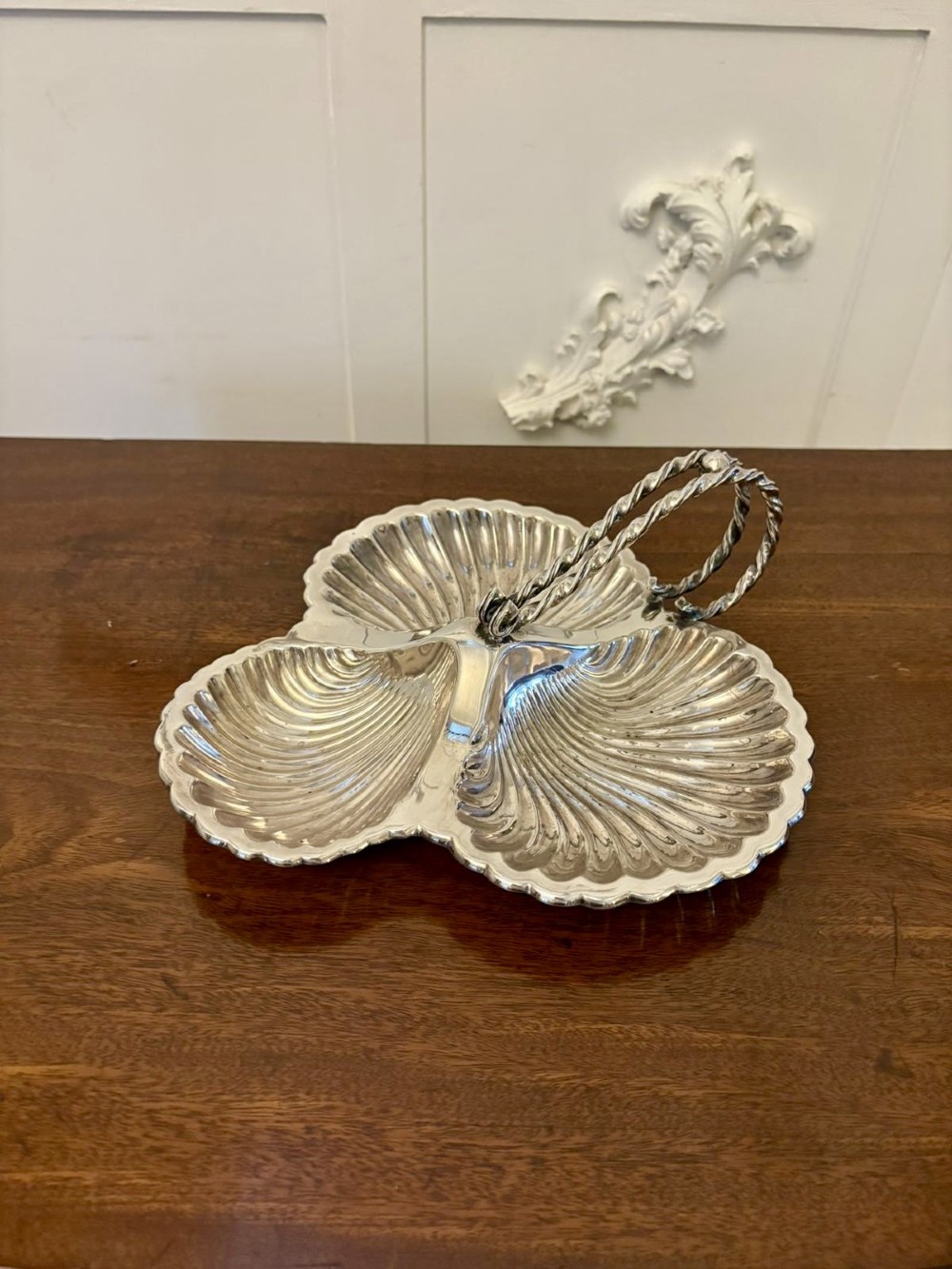 An Edwardian silver-plated tripartite serving dish featuring three fluted shell-shaped compartments joined by a central twisted handle. View V