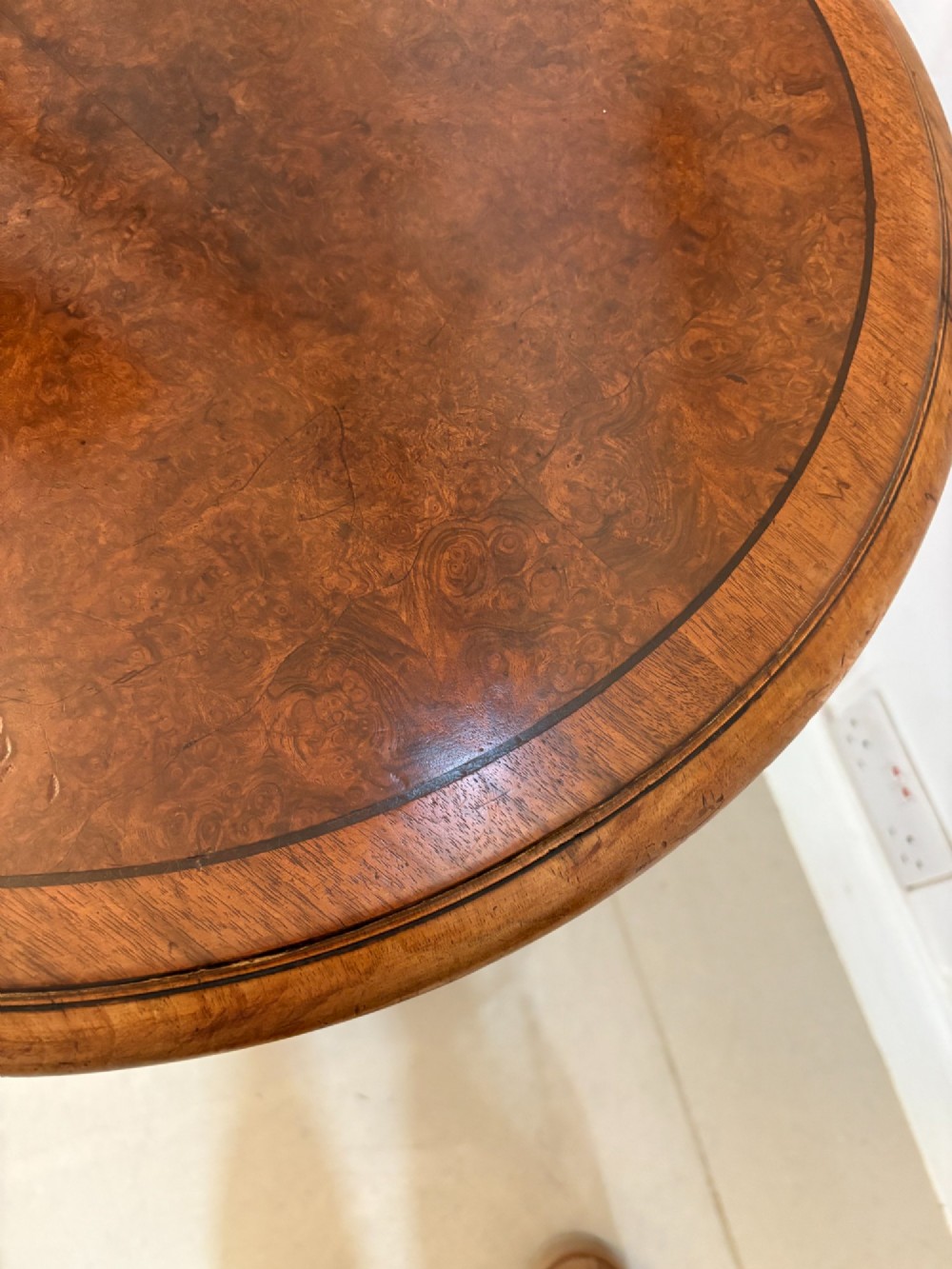 An antique Victorian burr walnut centre table featuring a shaped top with marquetry inlay, turned fluted legs, an X-frame stretcher, and ceramic castors. View V