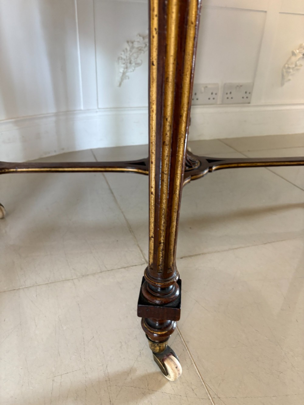 An antique Victorian burr walnut centre table featuring a shaped top with marquetry inlay, turned fluted legs, an X-frame stretcher, and ceramic castors. View VIII