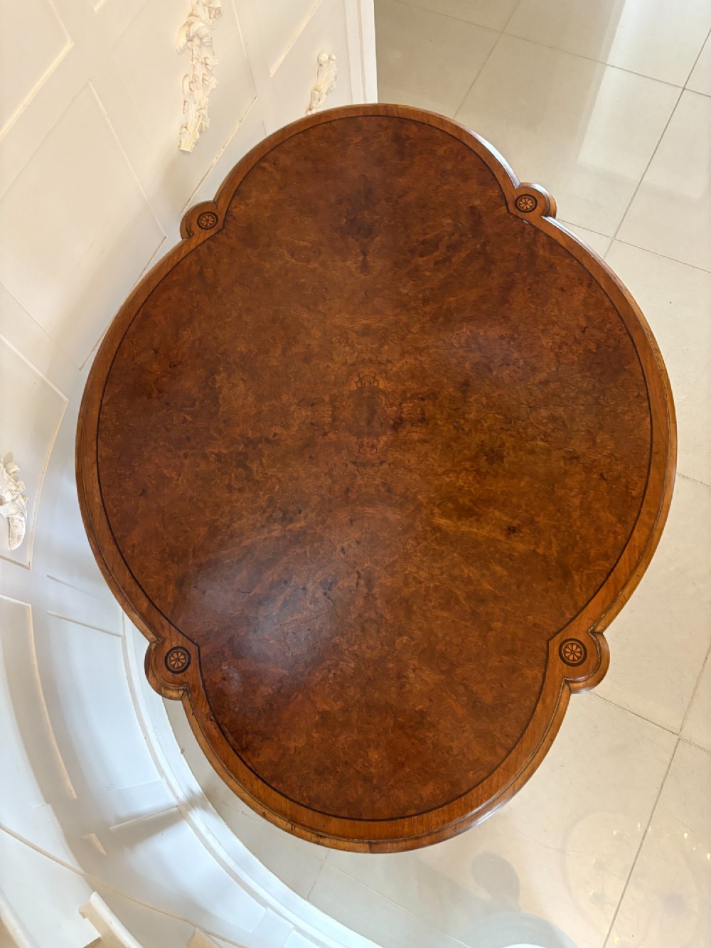 An antique Victorian burr walnut centre table featuring a shaped top with marquetry inlay, turned fluted legs, an X-frame stretcher, and ceramic castors. View XI