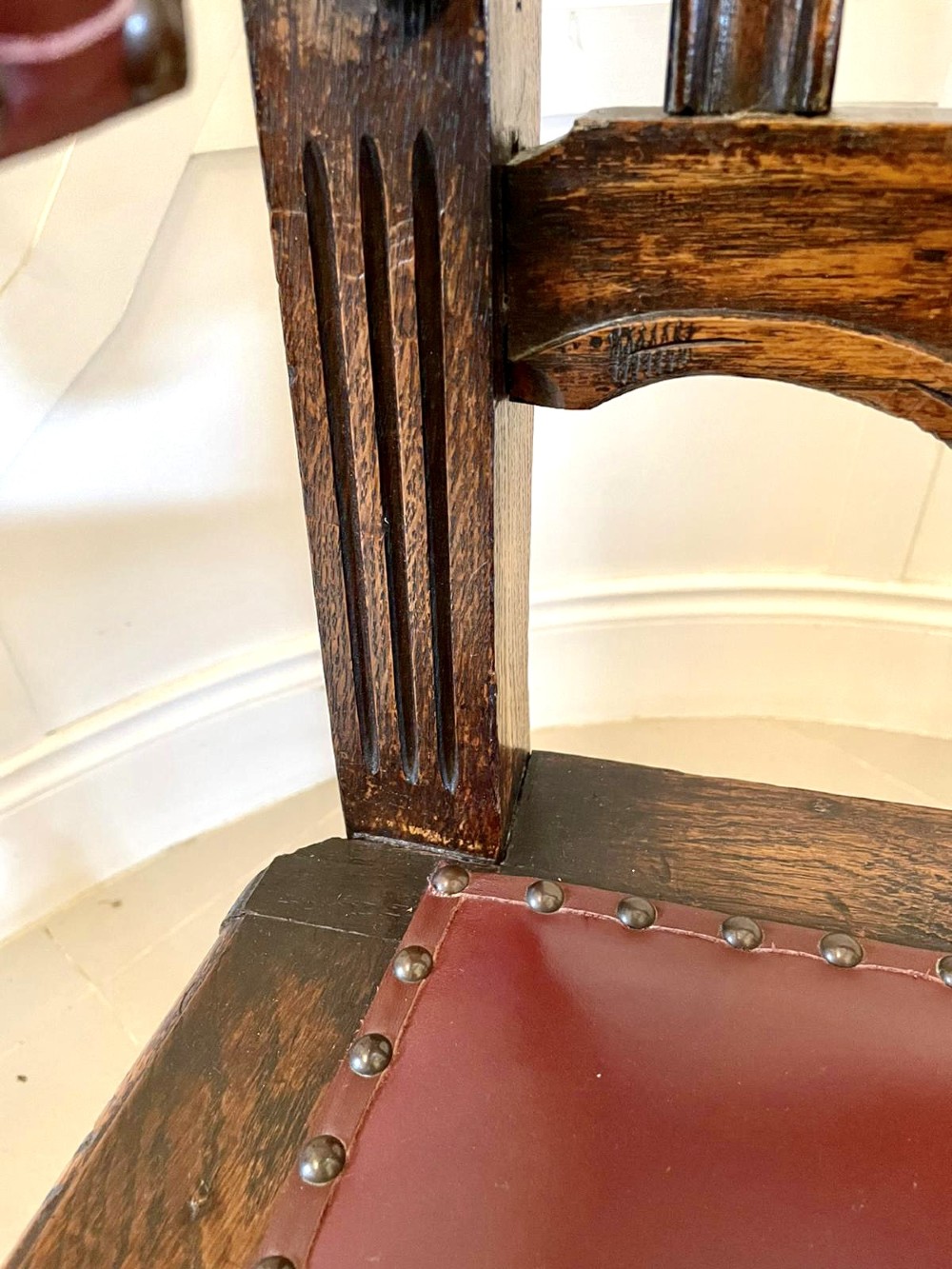 A high-backed Victorian carved oak armchair featuring barley twist supports, acanthus leaf carvings, and a burgundy leather seat with brass stud detail. View III