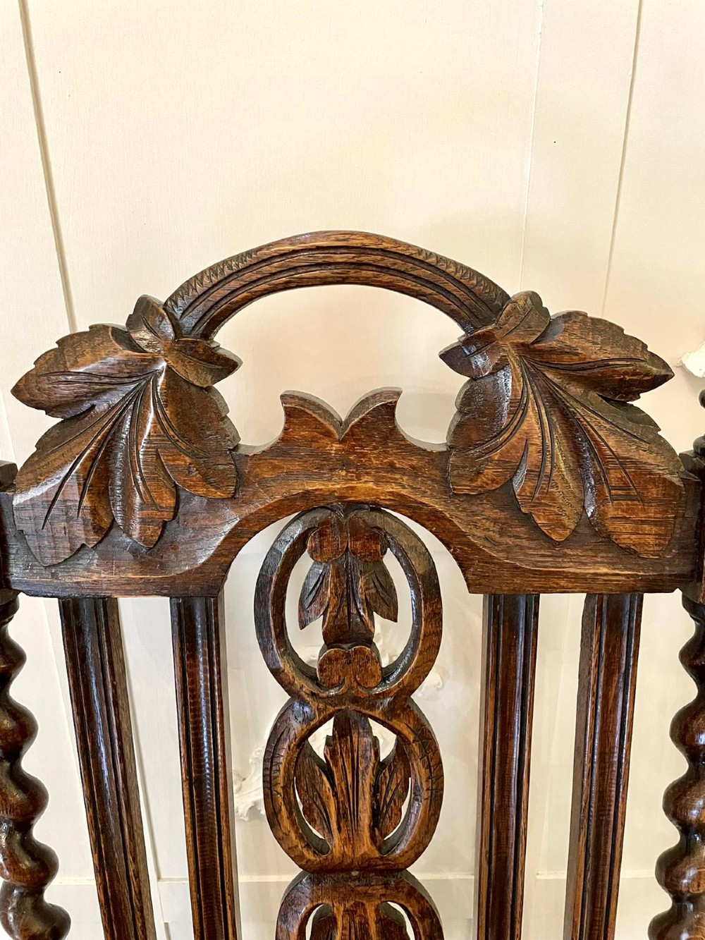 A high-backed Victorian carved oak armchair featuring barley twist supports, acanthus leaf carvings, and a burgundy leather seat with brass stud detail. View XIV