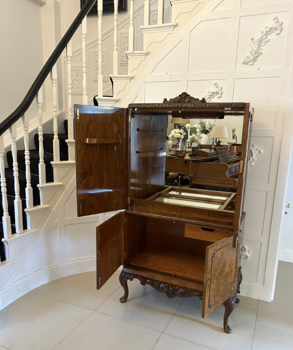An antique burr walnut cocktail cabinet featuring two upper doors with ornate brass hardware, set on carved cabriole legs. View V