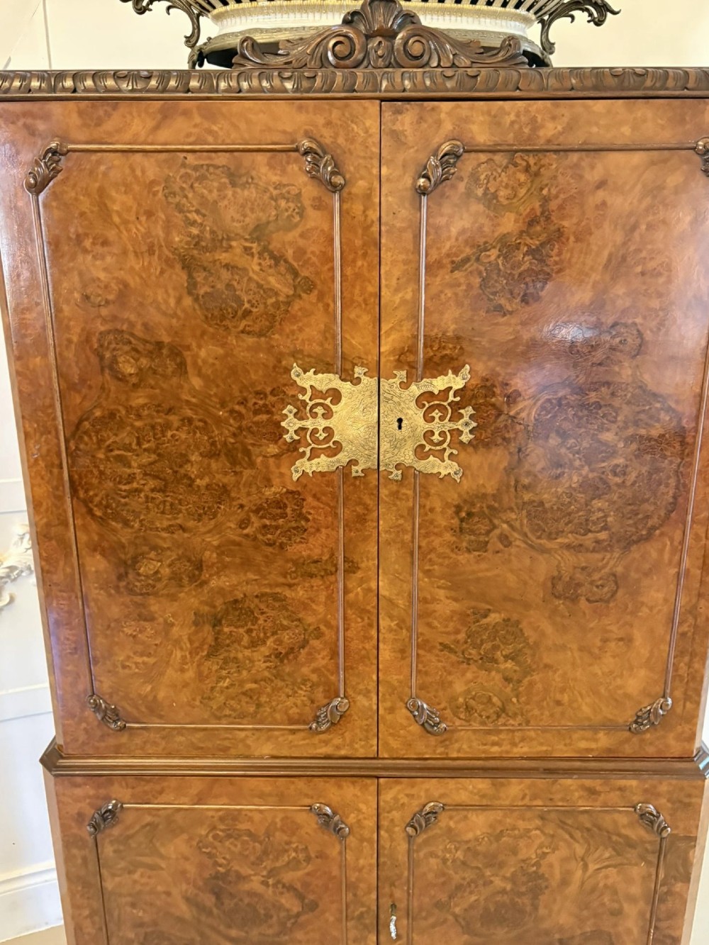 An antique burr walnut cocktail cabinet featuring two upper doors with ornate brass hardware, set on carved cabriole legs. View VIII