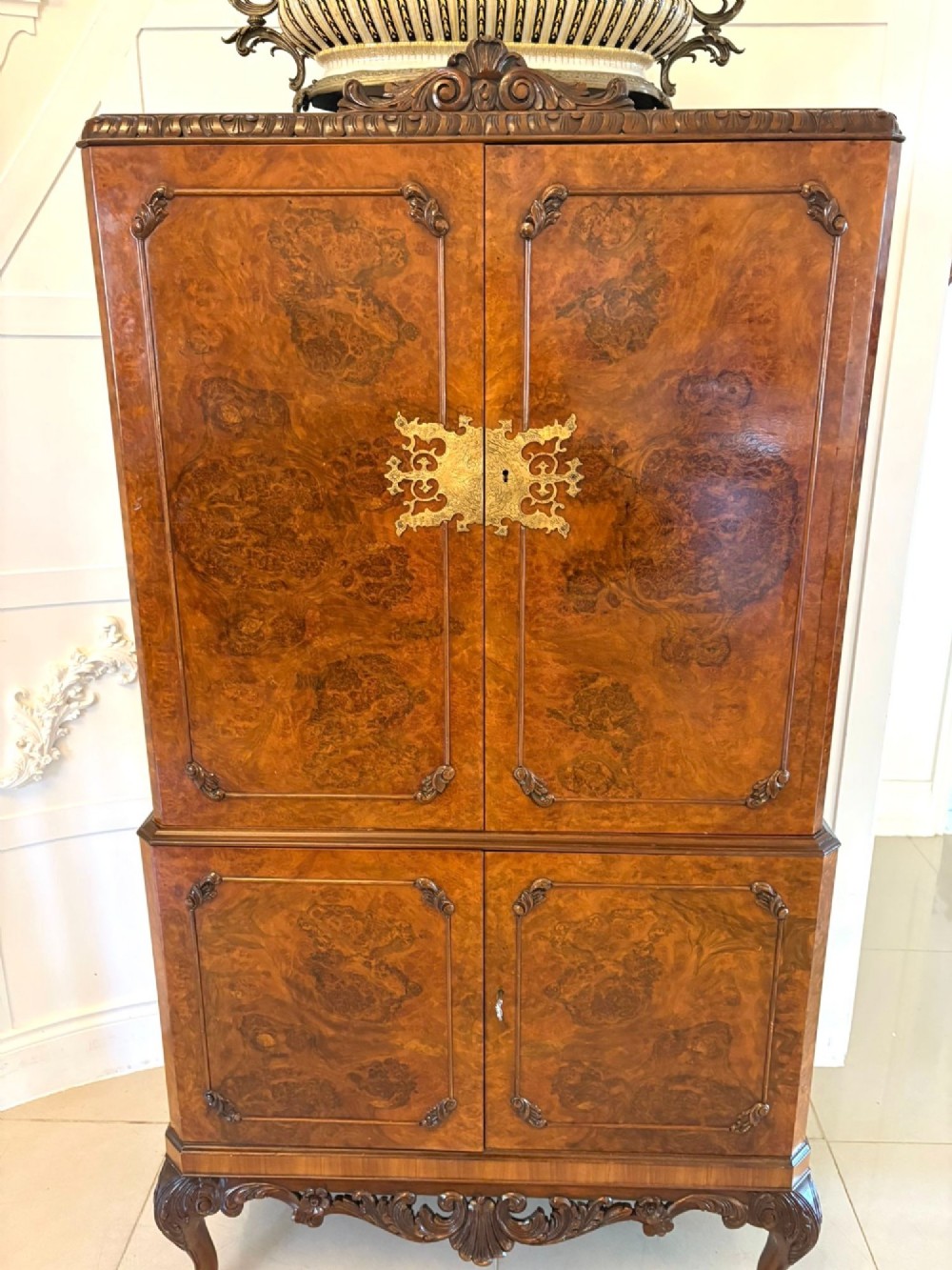 An antique burr walnut cocktail cabinet featuring two upper doors with ornate brass hardware, set on carved cabriole legs. View XI
