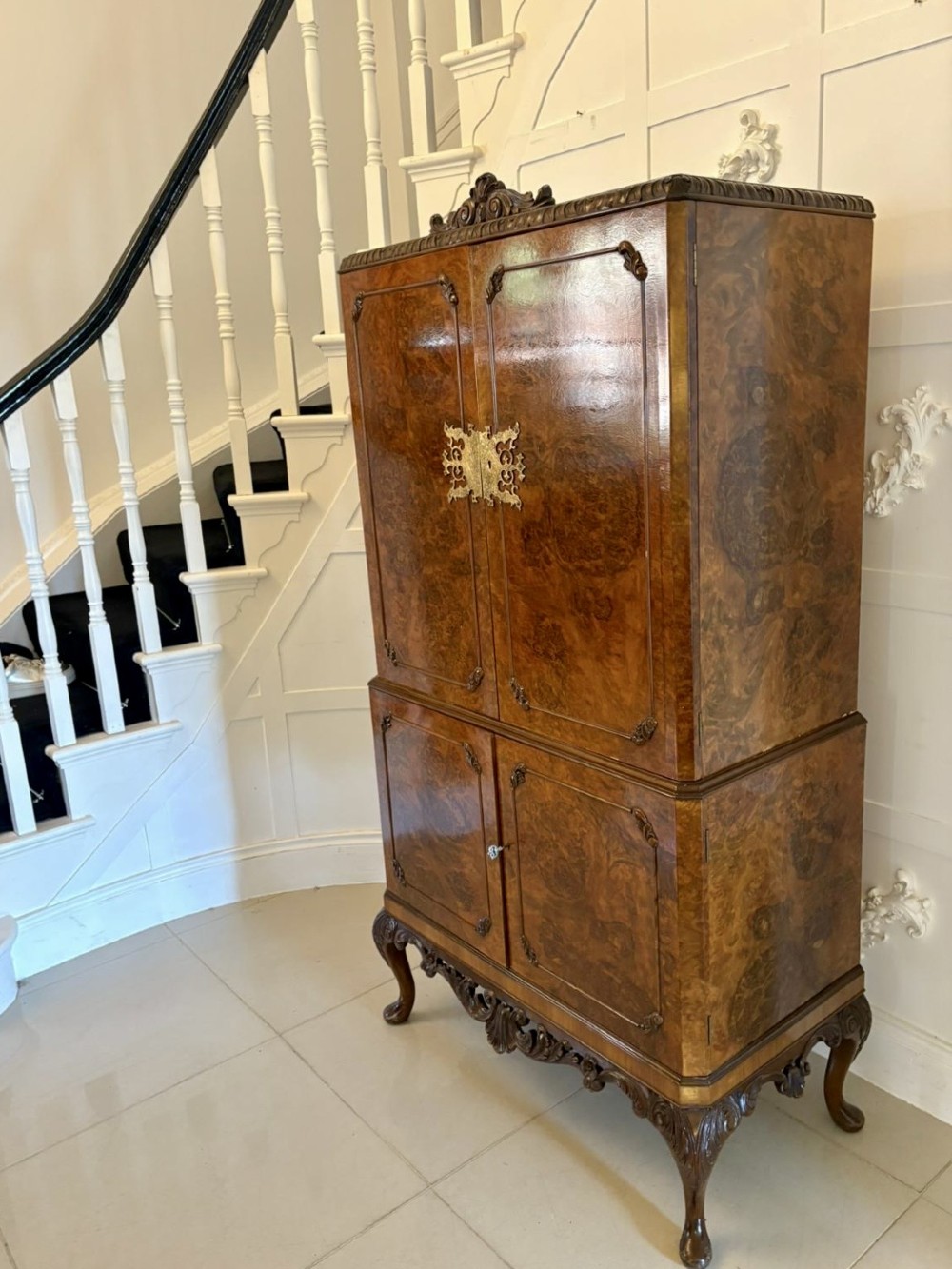 An antique burr walnut cocktail cabinet featuring two upper doors with ornate brass hardware, set on carved cabriole legs. View XIII