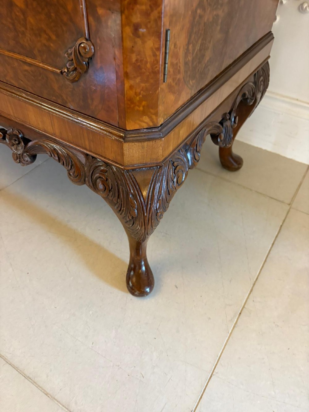 An antique burr walnut cocktail cabinet featuring two upper doors with ornate brass hardware, set on carved cabriole legs. View XIV