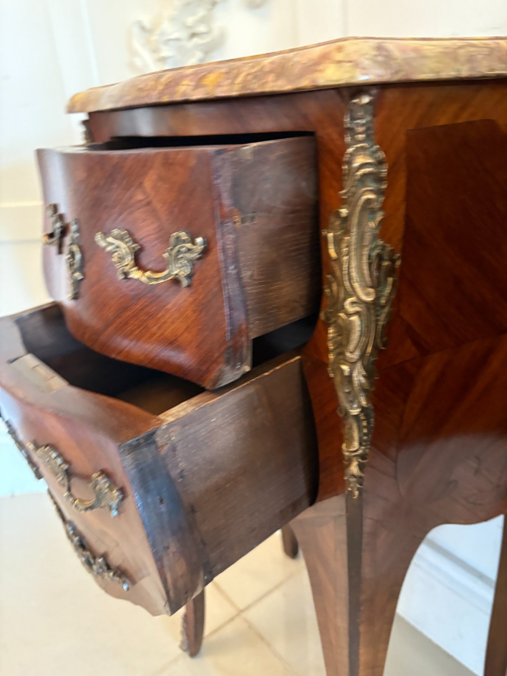 A pair of French Louis XV style kingwood bedside cabinets featuring two drawers, marquetry inlay, gilt bronze mounts, and serpentine marble tops. View III