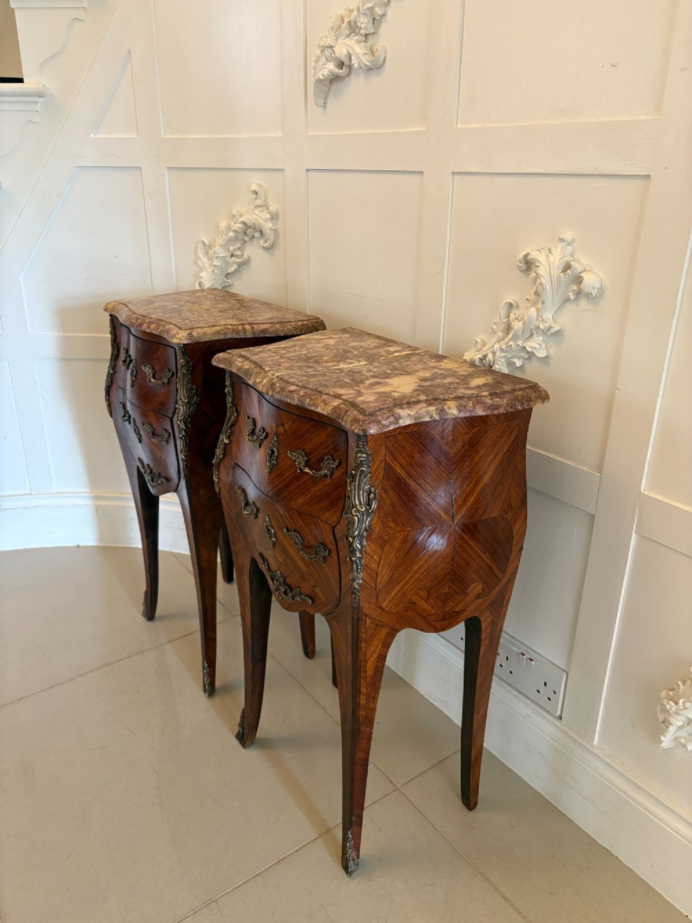 A pair of French Louis XV style kingwood bedside cabinets featuring two drawers, marquetry inlay, gilt bronze mounts, and serpentine marble tops. View XIII