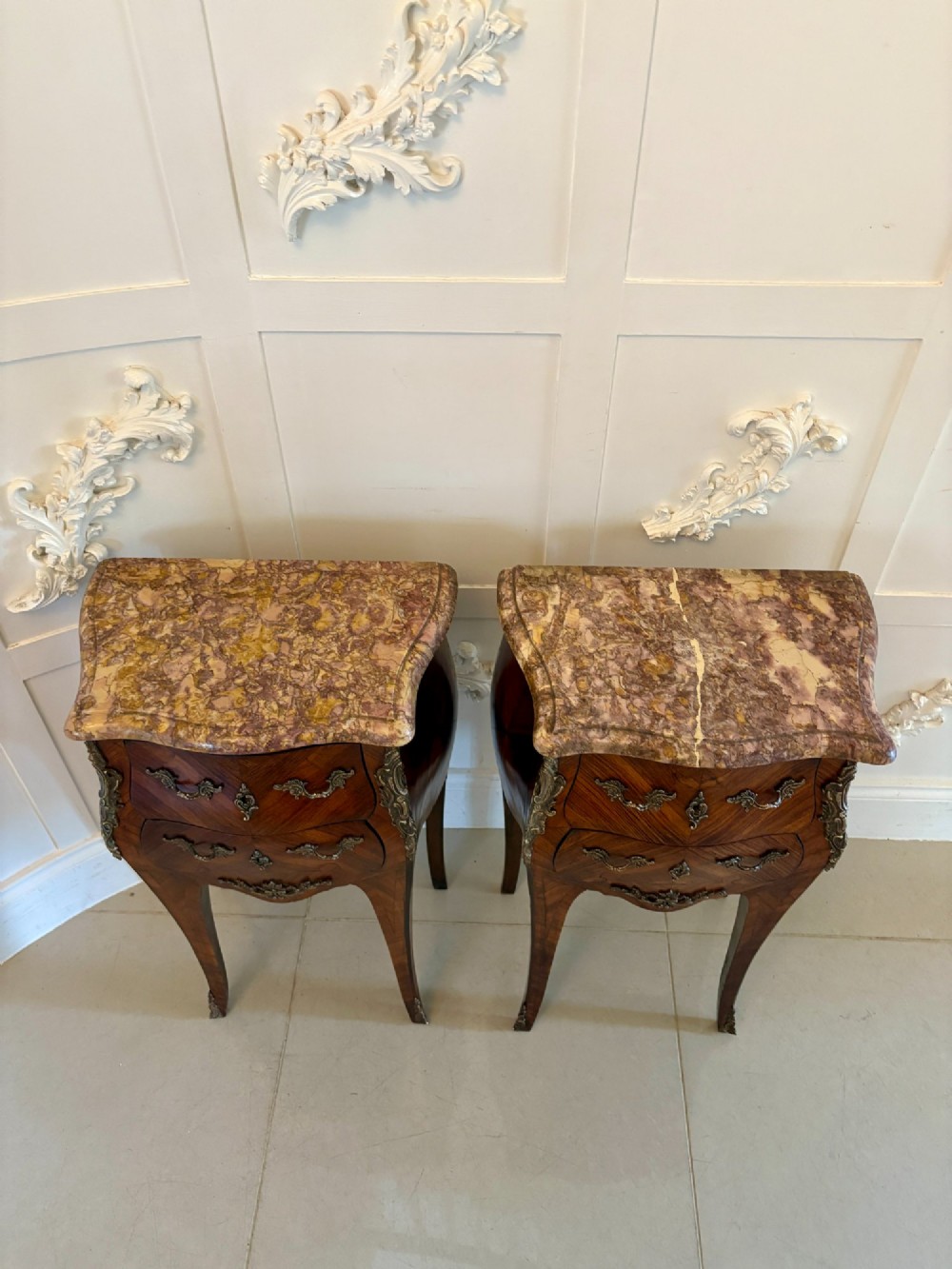 A pair of French Louis XV style kingwood bedside cabinets featuring two drawers, marquetry inlay, gilt bronze mounts, and serpentine marble tops. View XIV