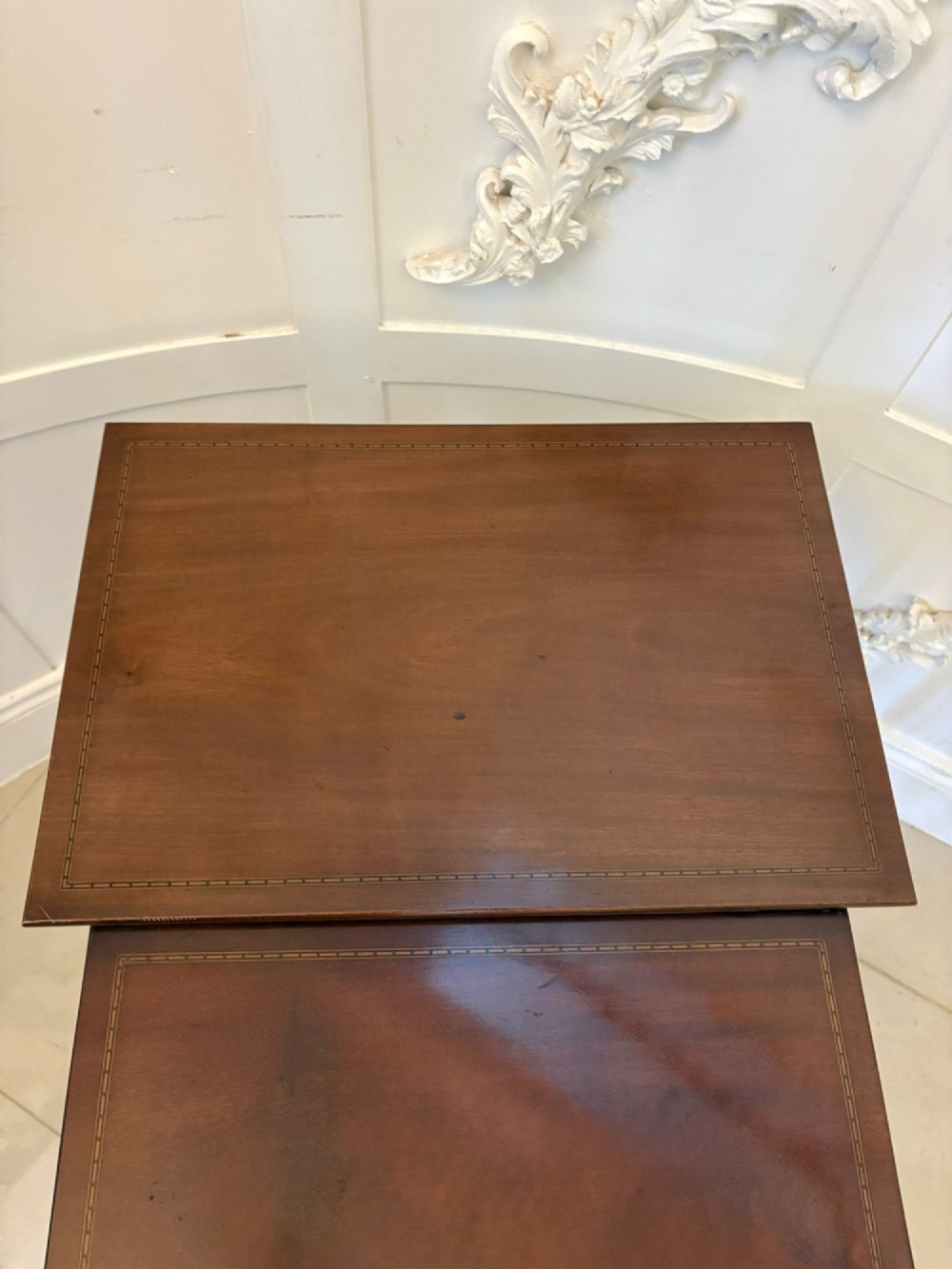 A set of four graduated Edwardian mahogany nesting tables featuring fine satinwood inlay borders and slender turned legs on trestle feet. View II
