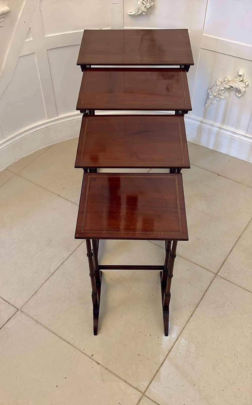 A set of four graduated Edwardian mahogany nesting tables featuring fine satinwood inlay borders and slender turned legs on trestle feet. View IV