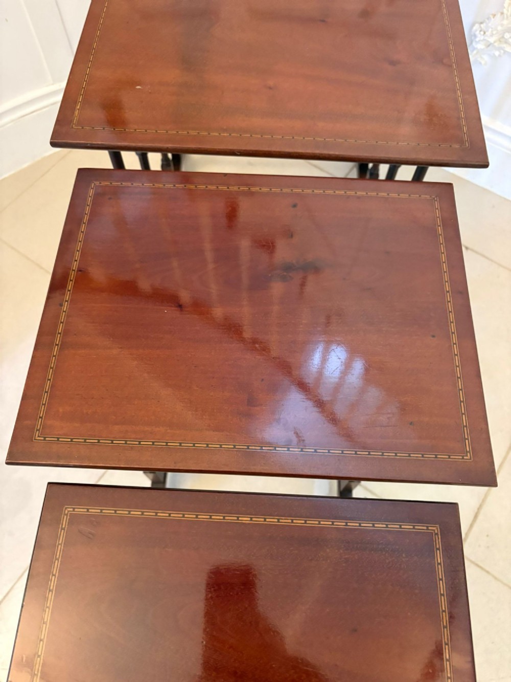 A set of four graduated Edwardian mahogany nesting tables featuring fine satinwood inlay borders and slender turned legs on trestle feet. View V
