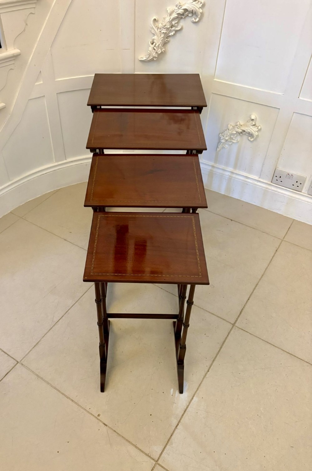 A set of four graduated Edwardian mahogany nesting tables featuring fine satinwood inlay borders and slender turned legs on trestle feet. View VI