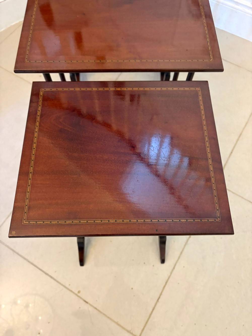 A set of four graduated Edwardian mahogany nesting tables featuring fine satinwood inlay borders and slender turned legs on trestle feet. View VII