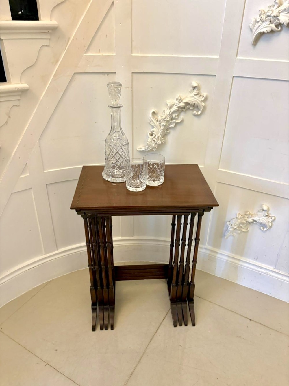 A set of four graduated Edwardian mahogany nesting tables featuring fine satinwood inlay borders and slender turned legs on trestle feet. View X